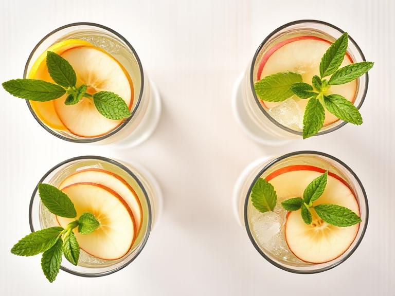 Top view of apple lemonade glasses arranged in a circle with fresh garnish
